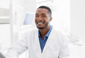 handsome black dentist smiling over modern dental 833H986 1