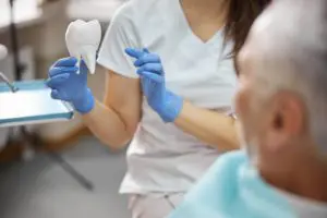 dental specialist showing a tooth replica to a pat 2021 09 03 14 18 27 utc 1