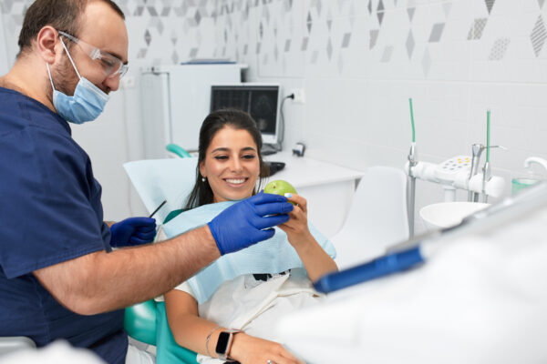 people, medicine, stomatology and health care concept - happy male dentist showing work plan to woman patient at dental clinic office.