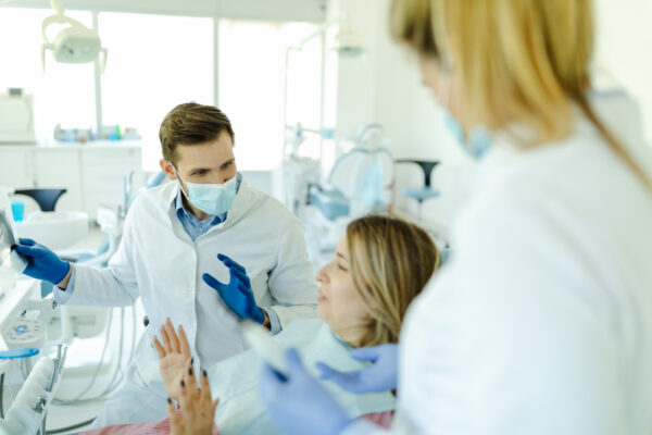 Photo of male dentist showing at patient's X-ray image in dental office.