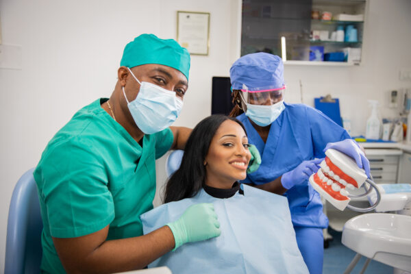 A patient smiles together with the dentist and the assistant during a dental visit.