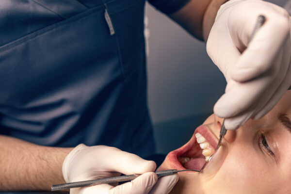 Dentist very carefully check up and repair tooth of his young female patient