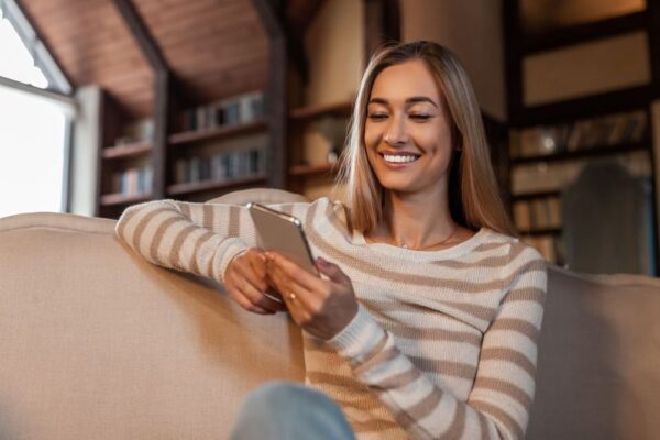 portrait-of-smiling-woman-using-cellphone-at-home-2022-10-07-02-08-27-utc (1)